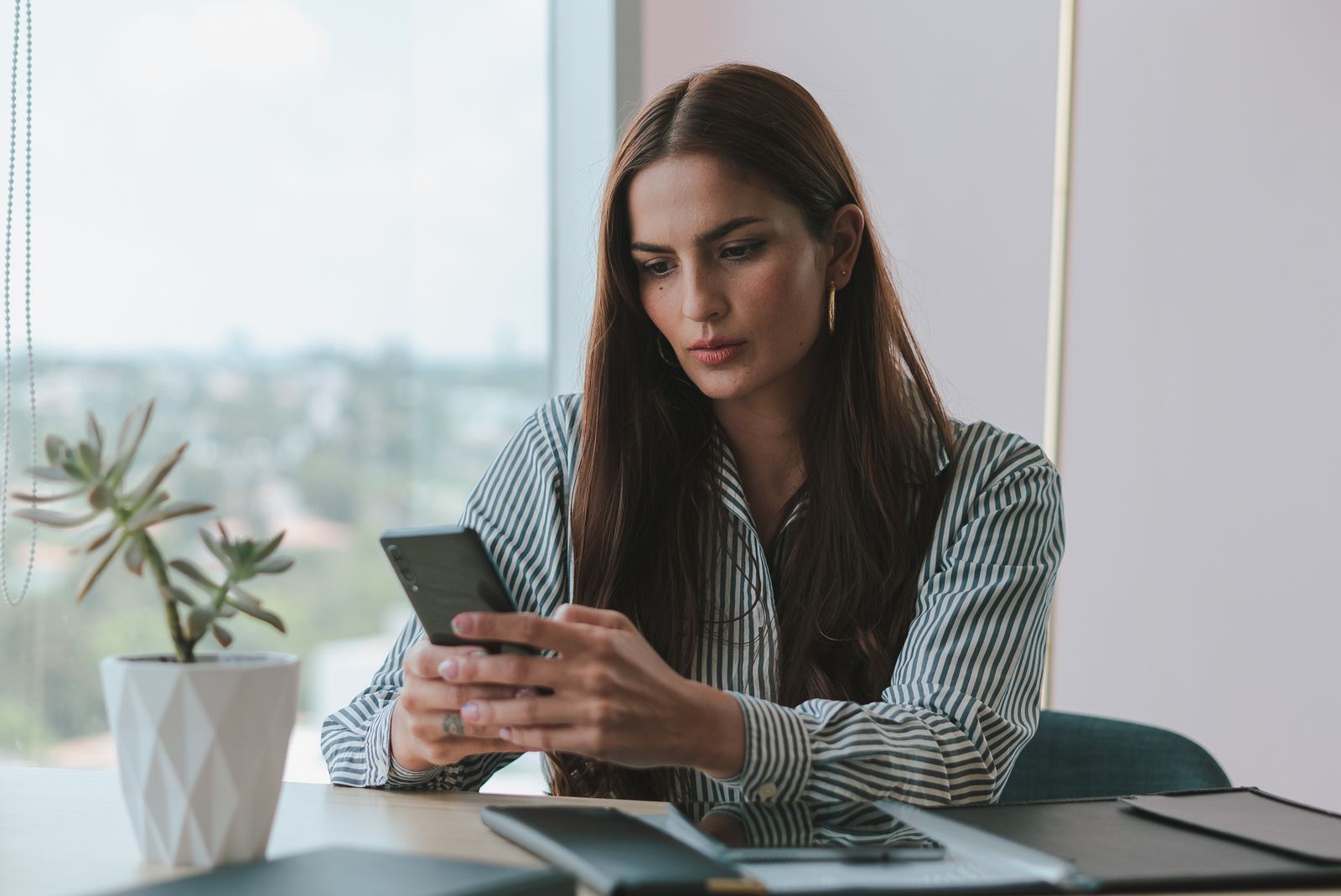 Atendente respondendo mensagens de clientes no celular, no escritório
