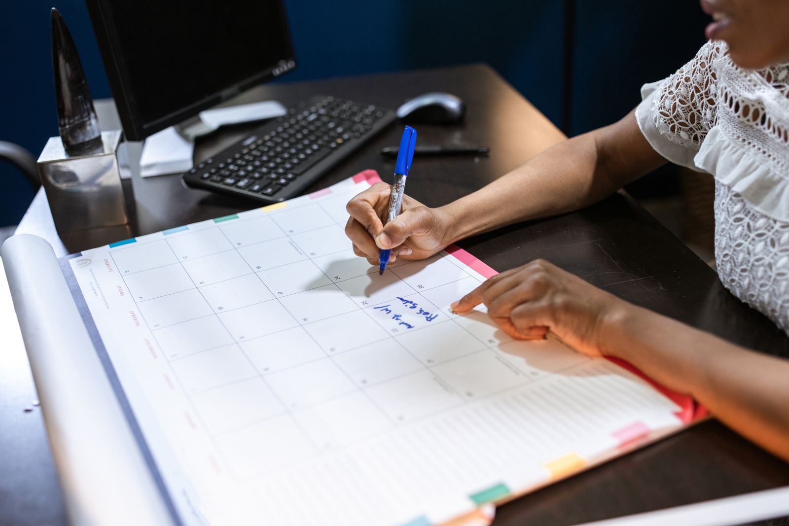 Mulher anotando compromissos em um calendário de mesa